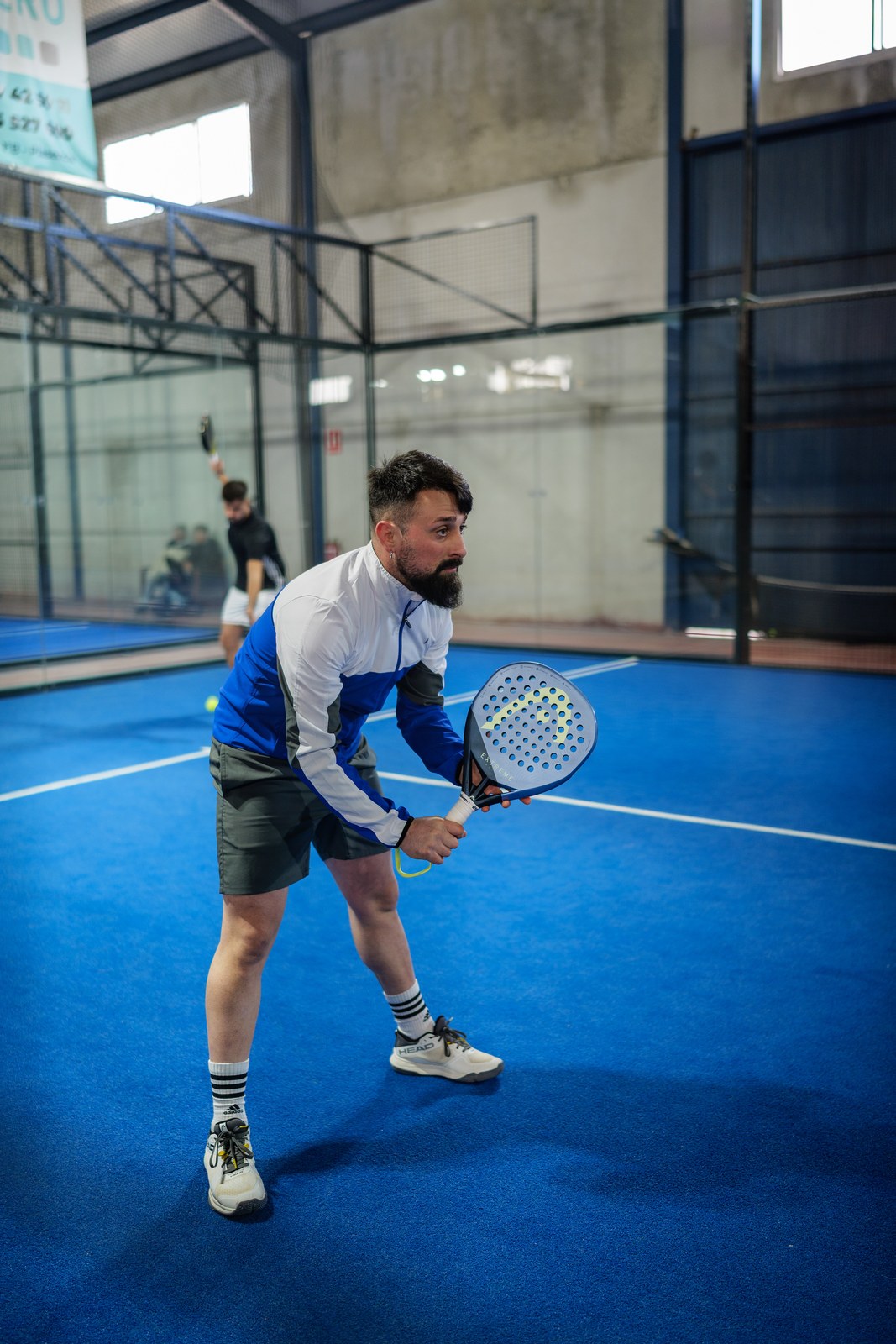 Padel player set in a ready position on an indoor blue court